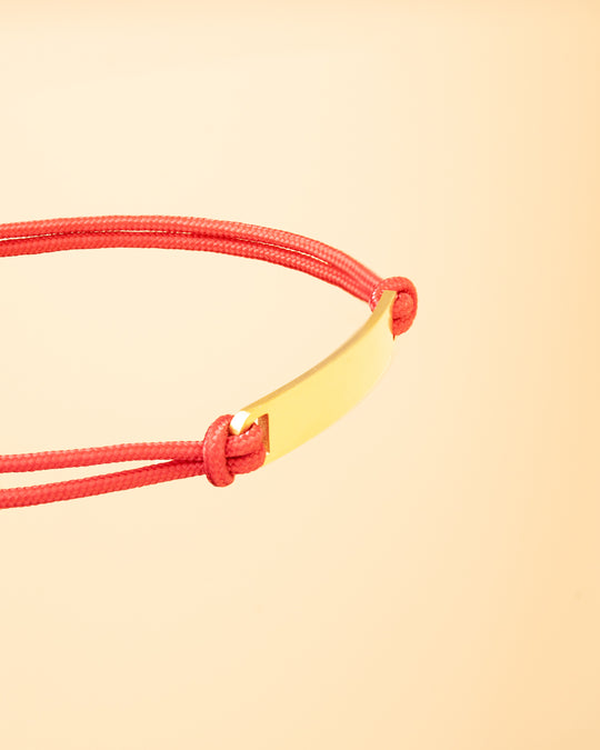 Red nylon bracelet with a gold-plated engraving plate